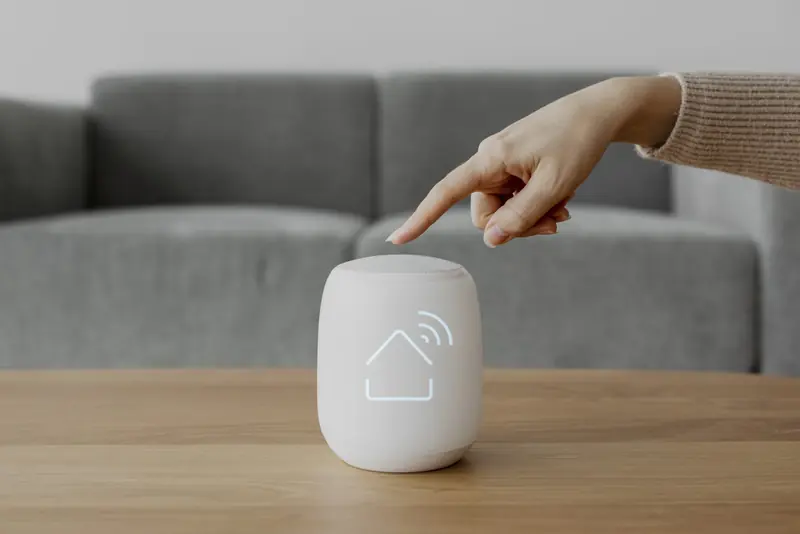 A finger touching a smart speaker on a coffee table